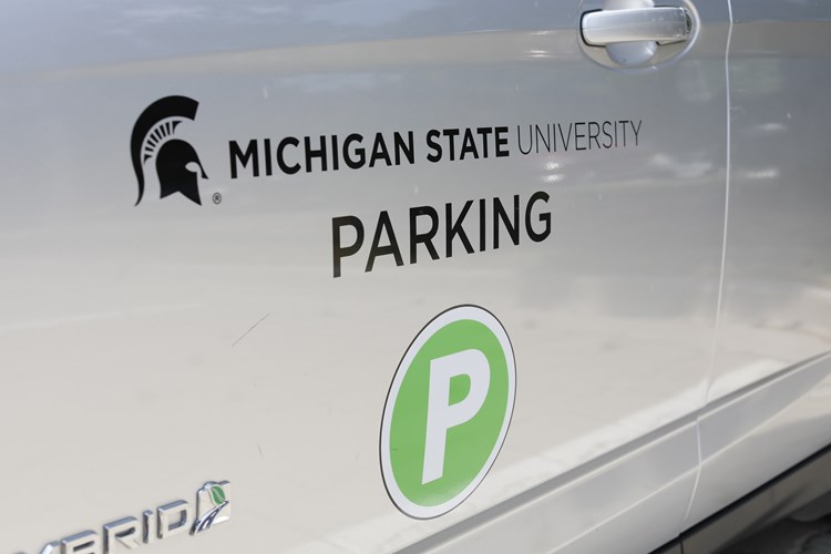 Silver vehicle with the words "Michigan State University Parking" and a green letter P